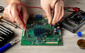 Engineer using needle-tip multimeter probes to test a populated printed circuit board on an ESD workbench